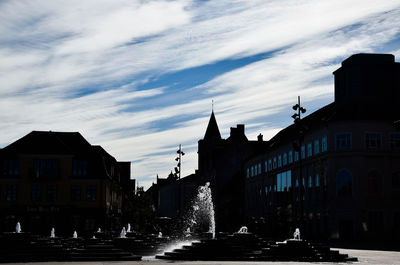 Buildings in city against cloudy sky