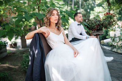 Thoughtful bride and bridegroom sitting on bench at park