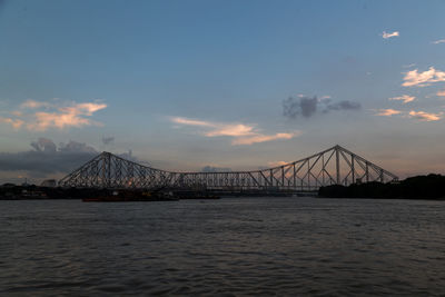 Suspension bridge over sea during sunset