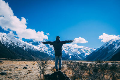 Man standing on field against snowcapped mountains