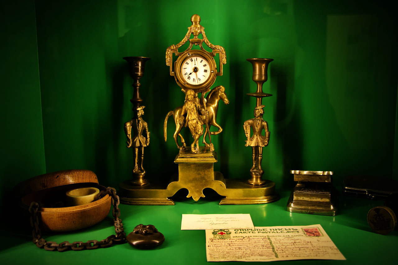 clock, indoors, green, no people, table, trophy, book, publication, gold, time, lighting equipment