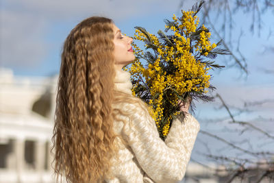 A woman with a bouquet of acacia flowers. the concept of the spring - march 8, easter, women's day.