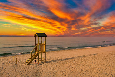Lifeguard tower on the beach with a dramatic red sunset