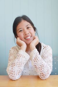 Portrait of smiling beautiful young woman with hands on chin