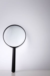 Close-up of magnifying glass against white background