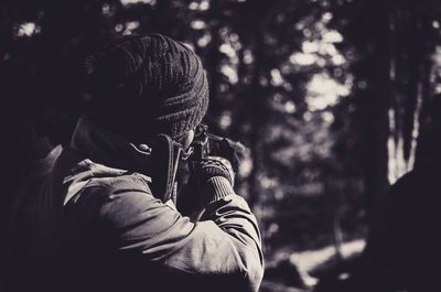 Rear view of man holding gun in forest