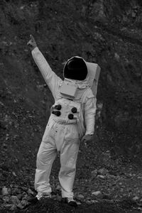 Full length of person in astronaut costume while pointing on field