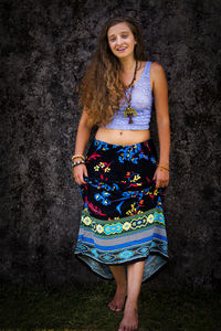 Portrait of smiling young woman standing against wall