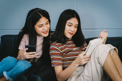 Beautiful young woman using smart phone while sitting on laptop