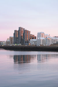 River by buildings against sky during sunset