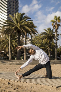 Man doing yoga on the beach at sunset