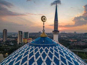 Clock tower amidst buildings in city against sky during sunset