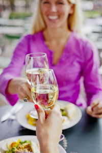 Two women toasting wine at outdoor cafe