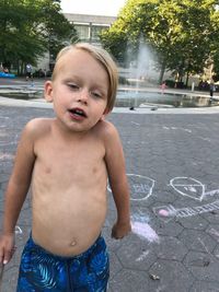 Full length of shirtless boy standing in city