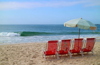 Chairs on beach against sky