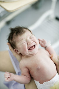 Close-up of crying baby girl held by mother at home