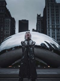 Portrait of young woman standing on car