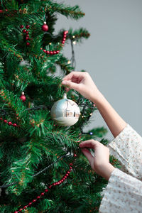 Cropped hands decorating christmas tree