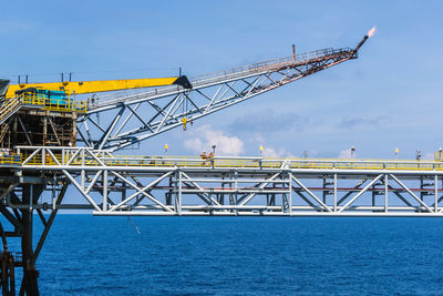 Low angle view of crane bridge against blue sky