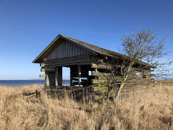 Abandoned house on field against clear blue sky