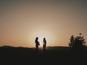 Silhouettes of a couple in nature while the sun hides in the mountains