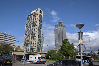 Cars on road by buildings against sky in city