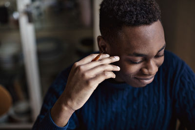 High angle view of smiling teenage boy holding pencil while studying at home