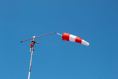 Low angle view of telephone pole against clear blue sky