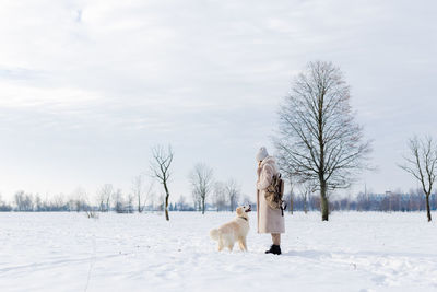 Young beautiful woman and her golden retriever dog having fun in winter.