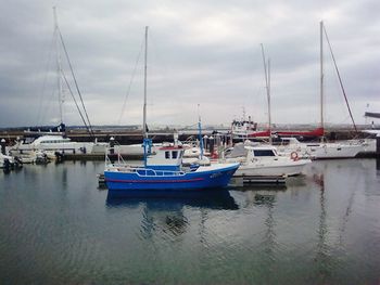 Boats moored at harbor against sky