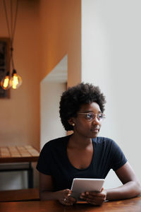 Young woman using phone while sitting on table