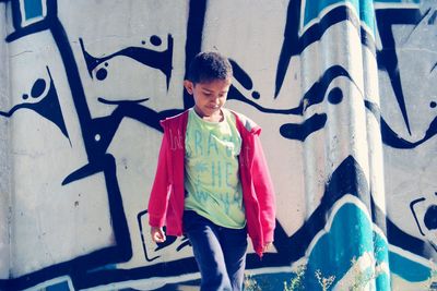 Boy walking against graffiti wall