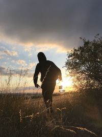 Silhouette man standing on field against sky during sunset