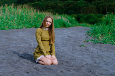 Young woman sitting on sand at beacj