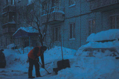 Full length of snow covered tree against building during winter