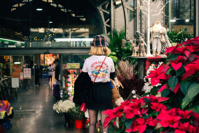 Rear view of woman standing by flowers in store