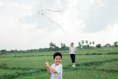 Full length of a siblings flying over field