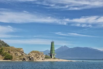 Lighthouse by sea against sky