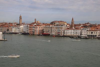 View of buildings at waterfront against cloudy sky