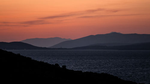 Scenic view of silhouette mountains and lake against romantic sky during sunset