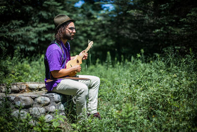 Man playing guitar while sitting outdoors