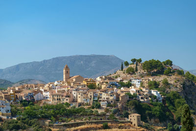 Townscape by mountains against clear blue sky