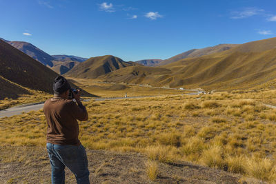 Rear view of man on arid landscape against sky