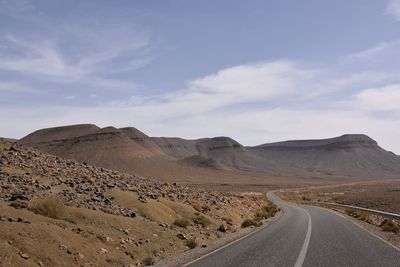 Road leading towards mountains against sky