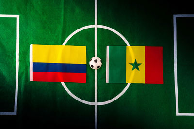 Directly above shot of figurine soccer field with flags of colombia and senegal 