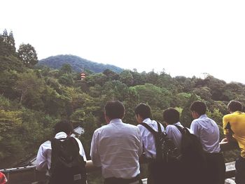 Rear view of people on mountain against clear sky