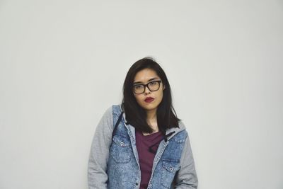 Portrait of beautiful young woman against wall