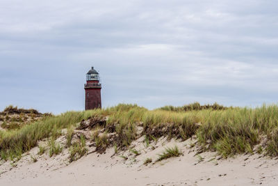 Lighthouse on beach against sky