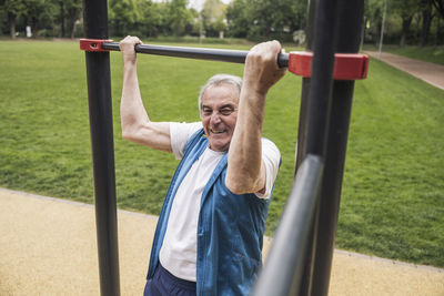 Active senior man exercising on gymnastics bar at park