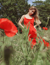 Young woman with red petals on field